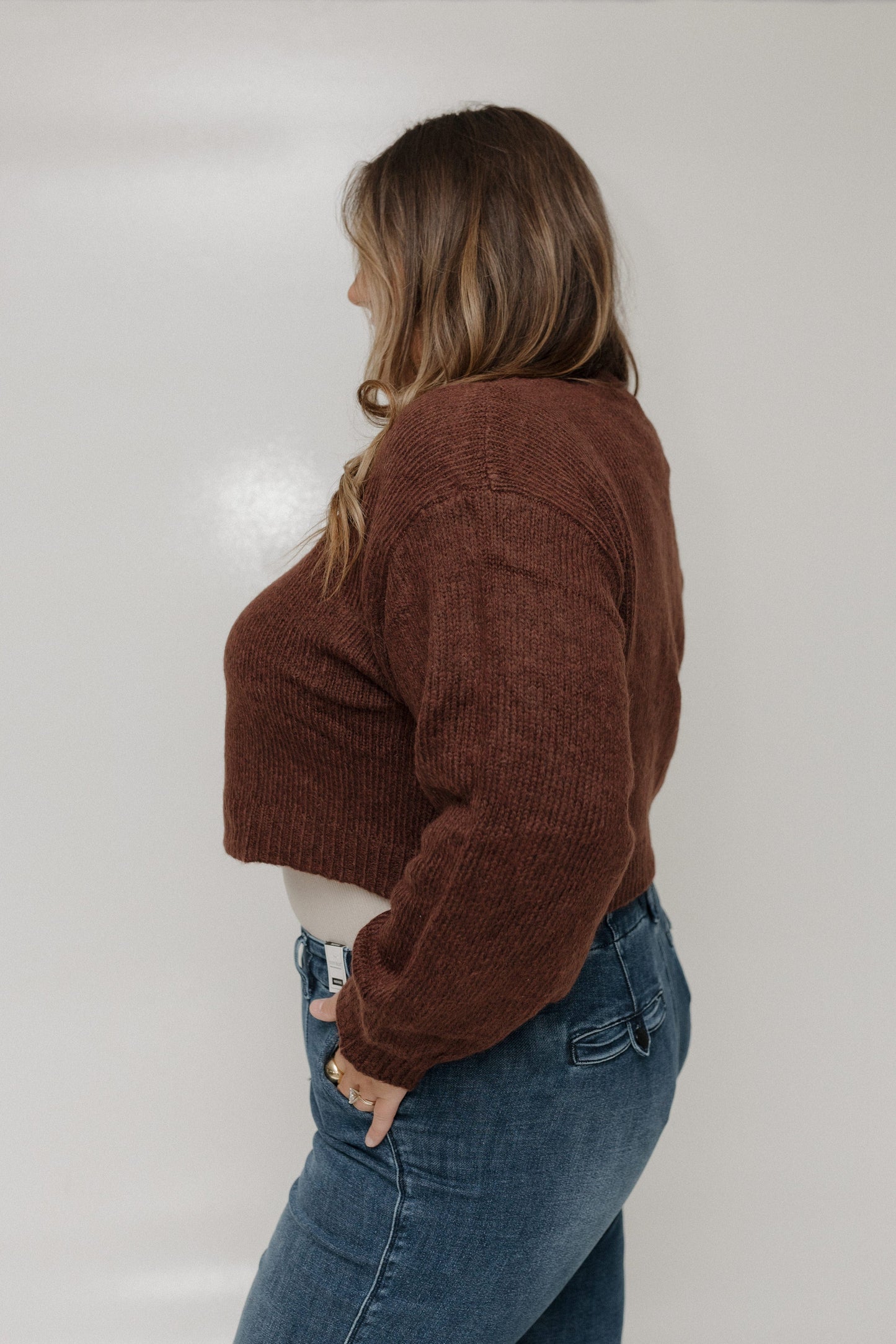 Person wearing a brown corduroy jacket and blue jeans against a white background