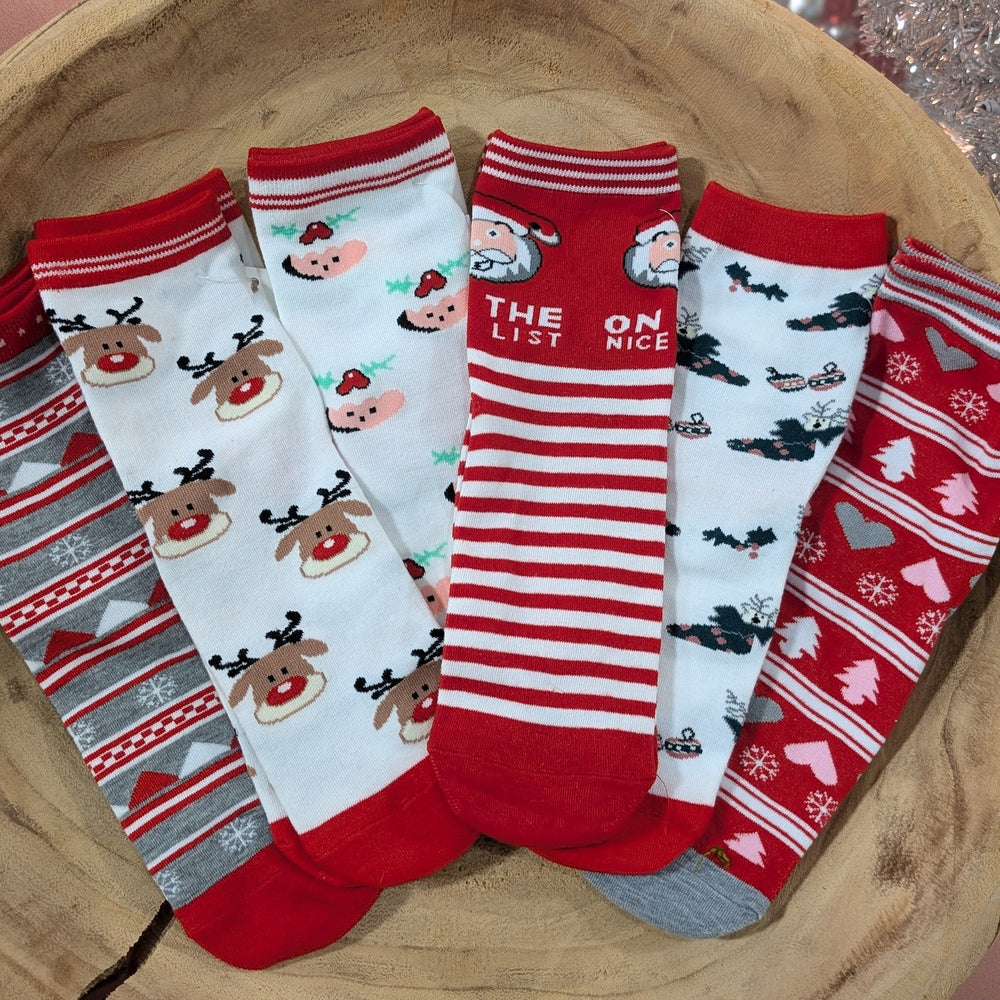 A wooden bowl holds six pairs of holiday socks in festive colors, featuring Christmas-themed patterns like reindeer, Santa, stripes, bats, and various holiday motifs—perfect for cozy nights.