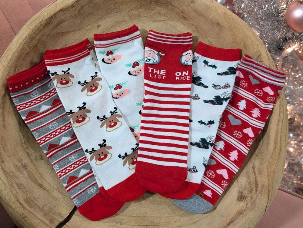 A wooden bowl holds six pairs of holiday socks in festive colors, featuring Christmas-themed patterns like reindeer, Santa, stripes, bats, and various holiday motifs—perfect for cozy nights.