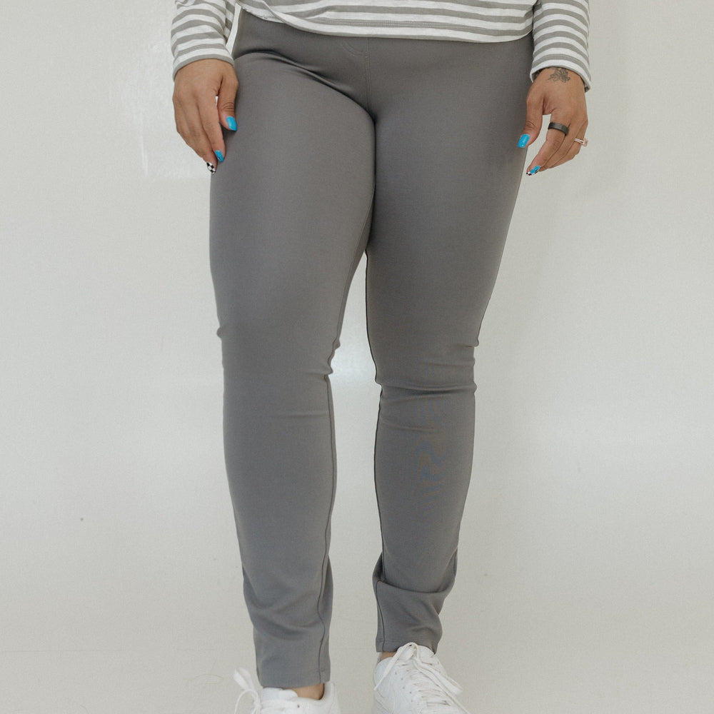 Person wearing gray jogger pants and a striped shirt on a plain background