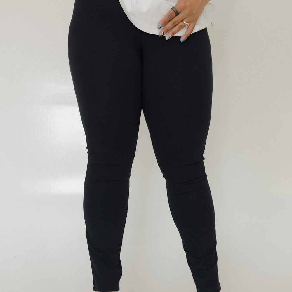 Person wearing black leggings and white shoes on a plain background