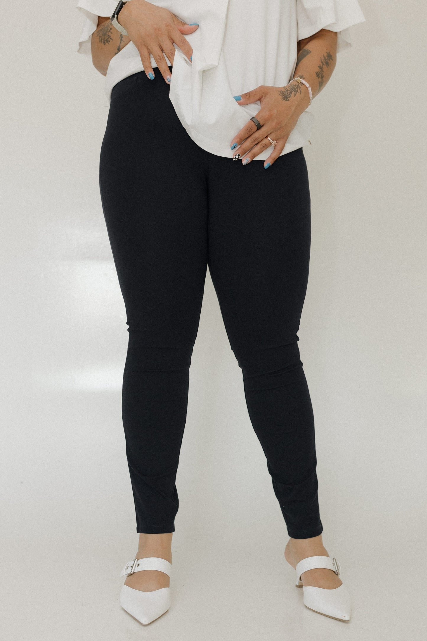 Person wearing black leggings and white shoes on a plain background