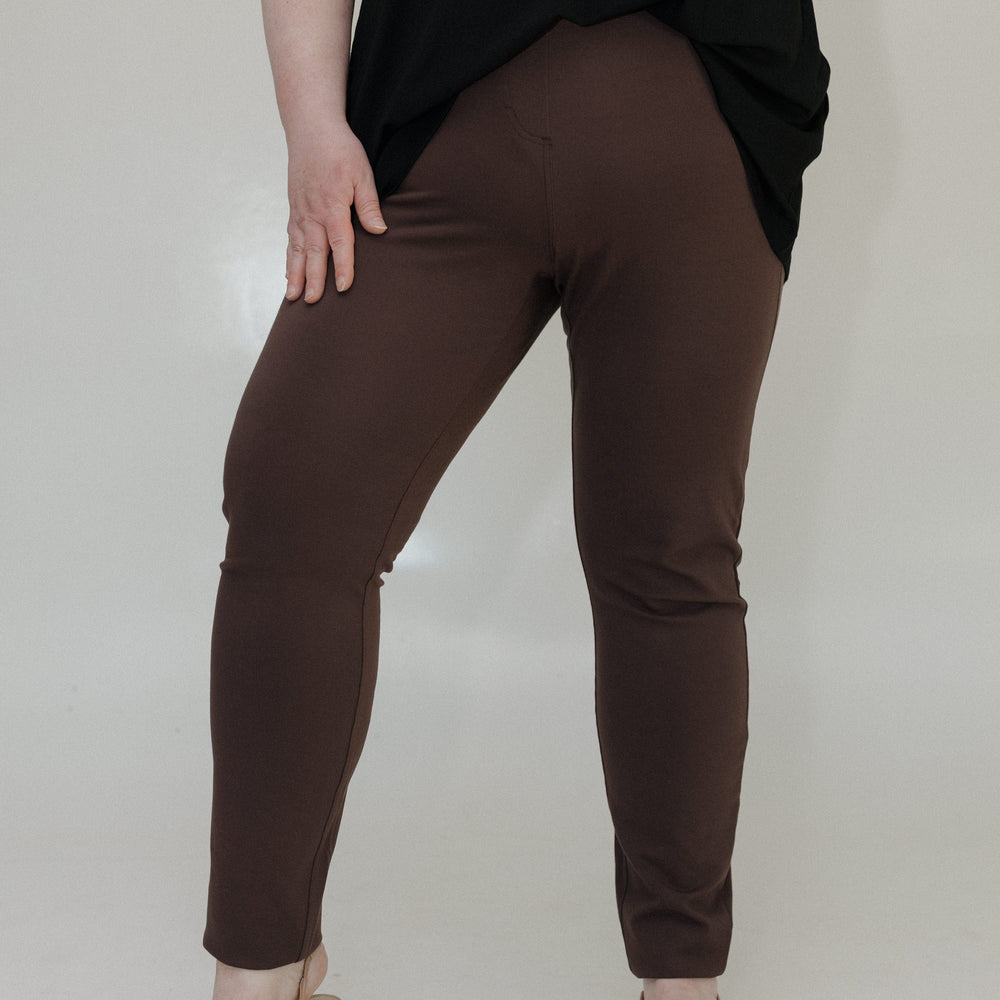 Person wearing brown pants and a black top on a white background
