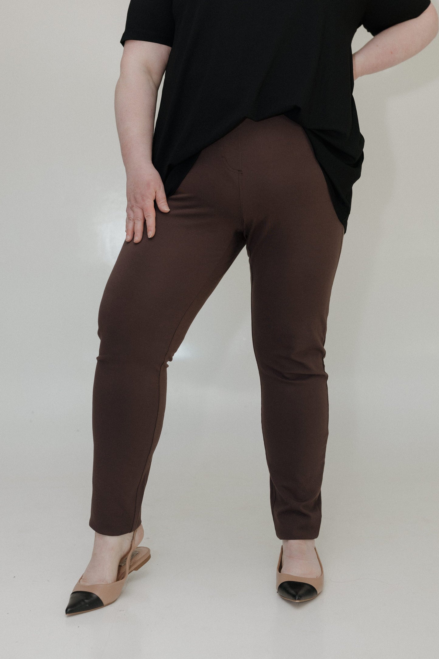 Person wearing brown pants and a black top on a white background