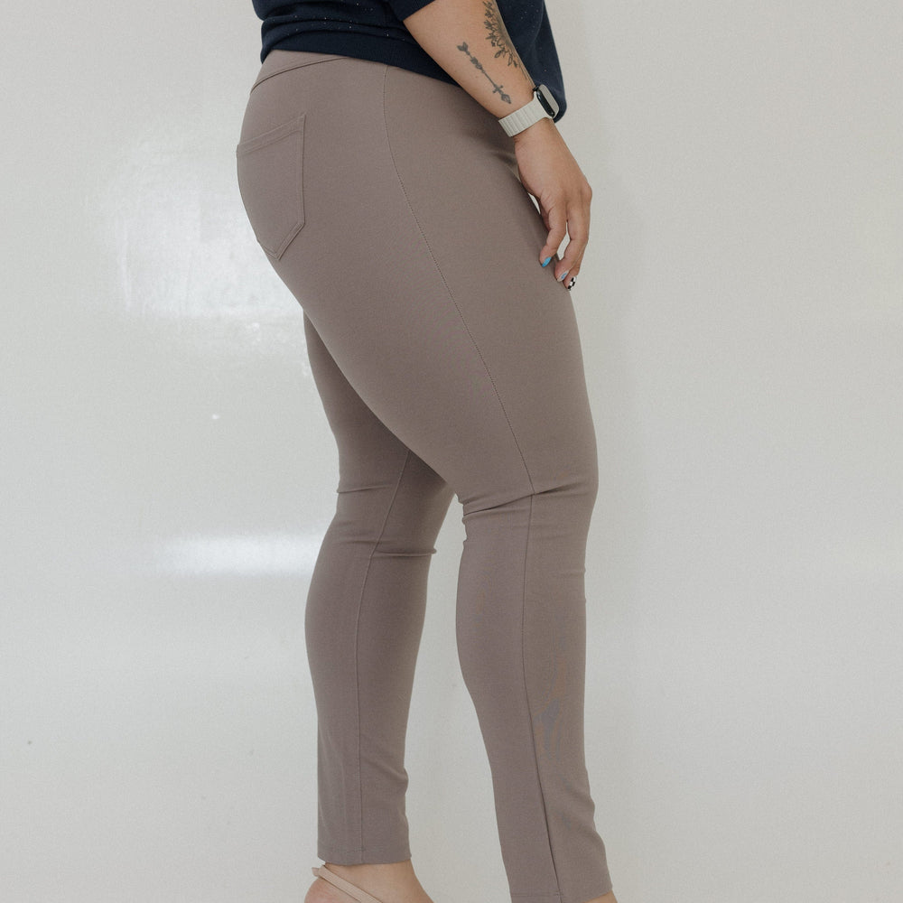 Person wearing beige pants and high heels on a plain background