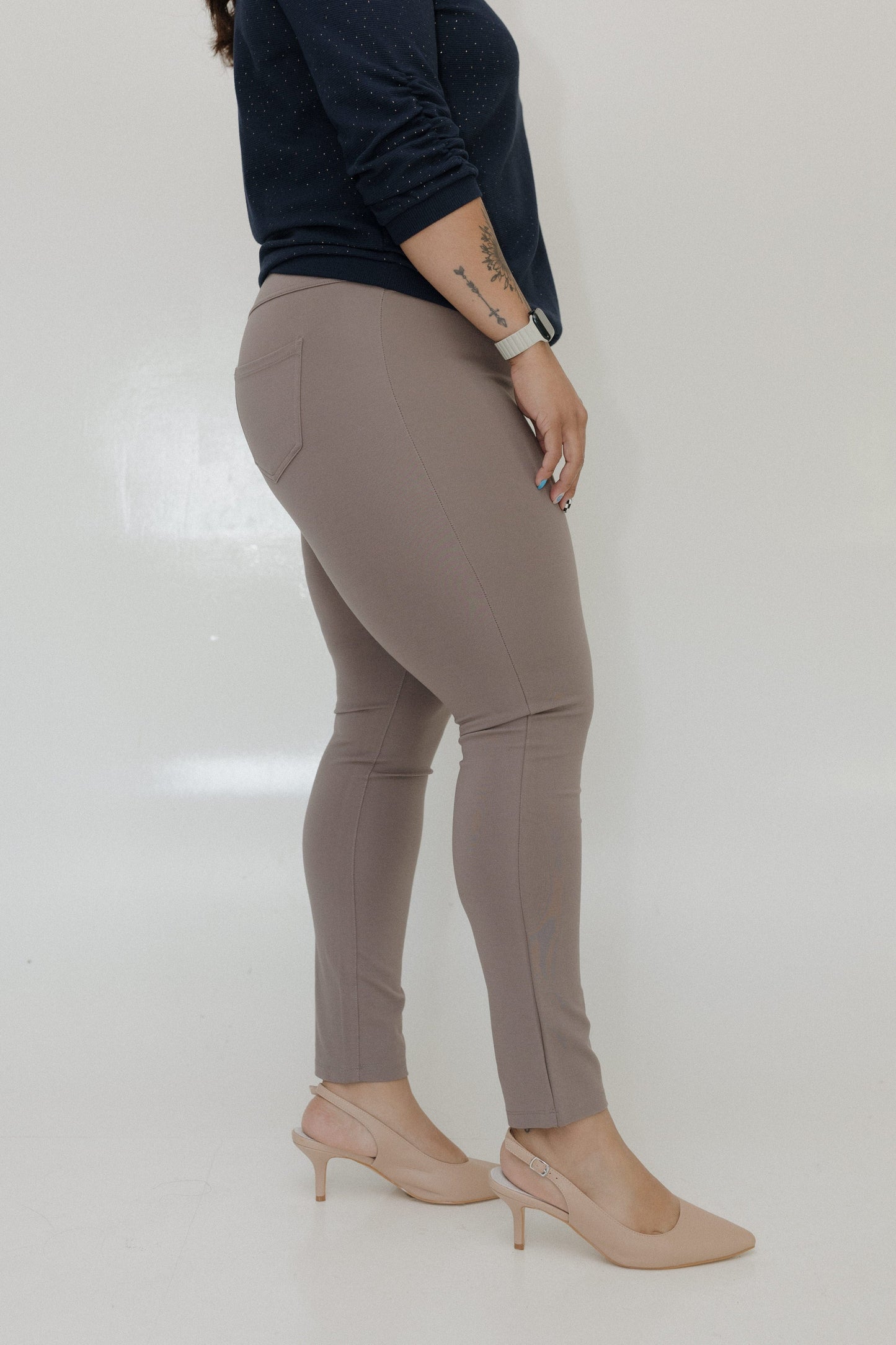 Person wearing beige pants and high heels on a plain background