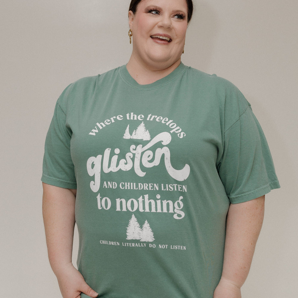 Person wearing a green t-shirt with white text and graphics on a plain background