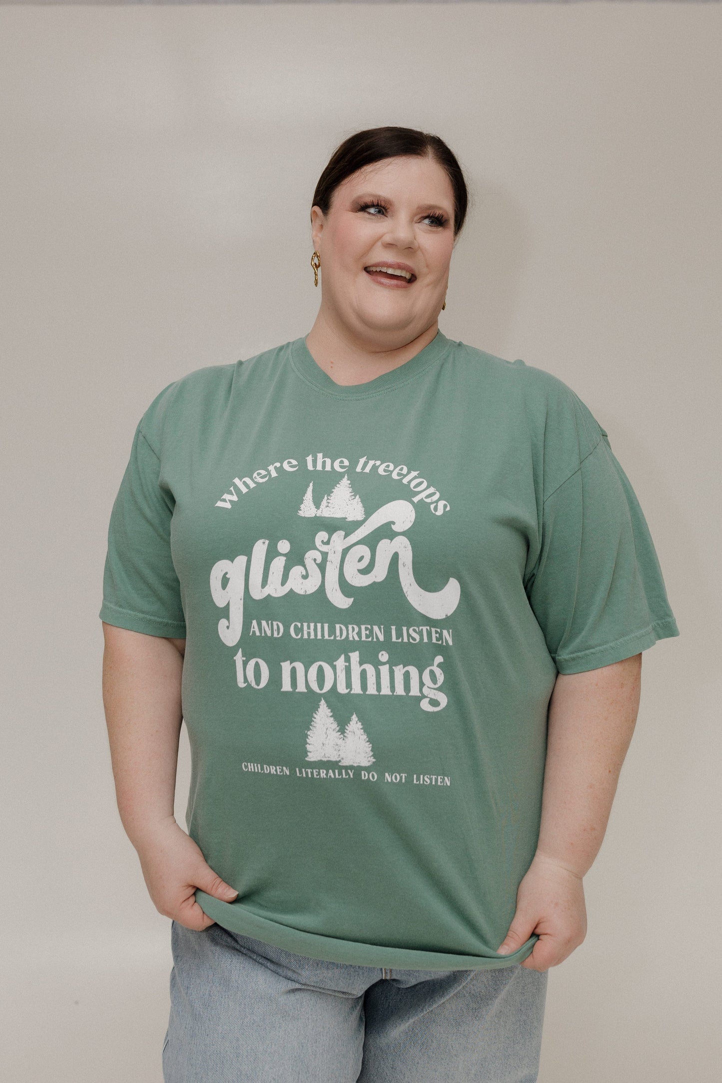 Person wearing a green t-shirt with white text and graphics on a plain background