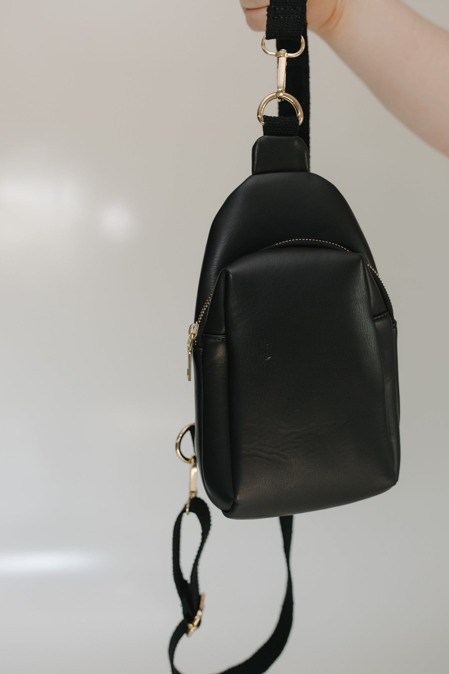 Black leather backpack with gold zippers on a light gray background