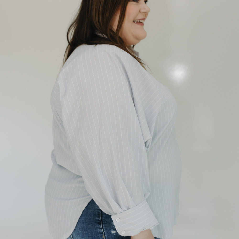 Woman wearing a light gray sweater and blue jeans against a white background