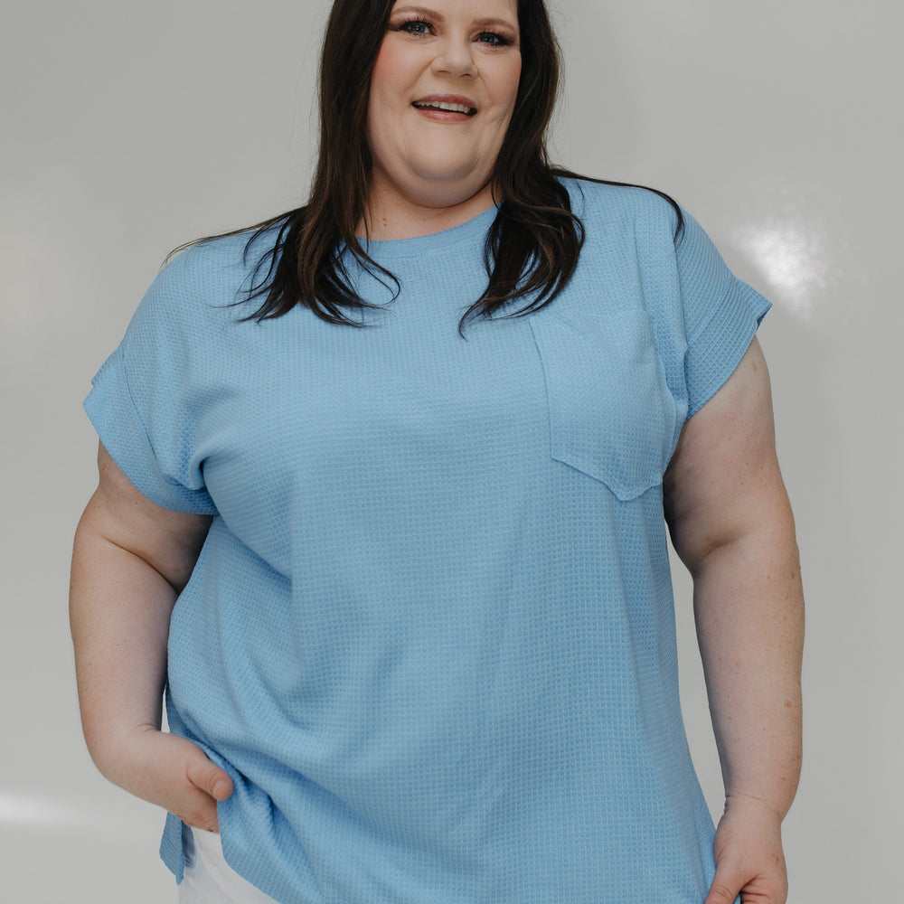 Person wearing a light blue t-shirt and white shorts against a plain background