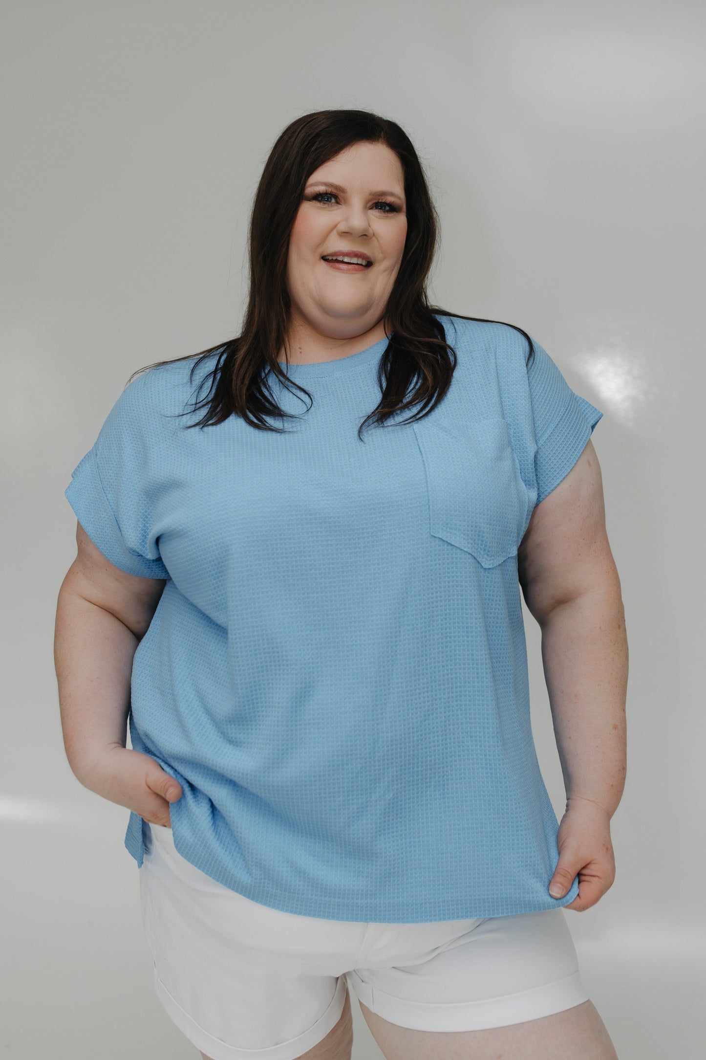 Person wearing a light blue t-shirt and white shorts against a plain background