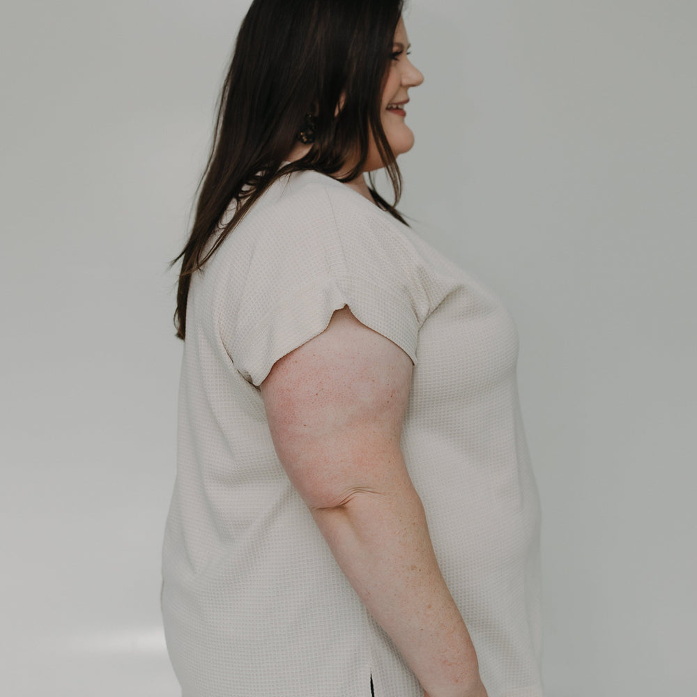 Woman wearing a light-colored blouse against a plain background