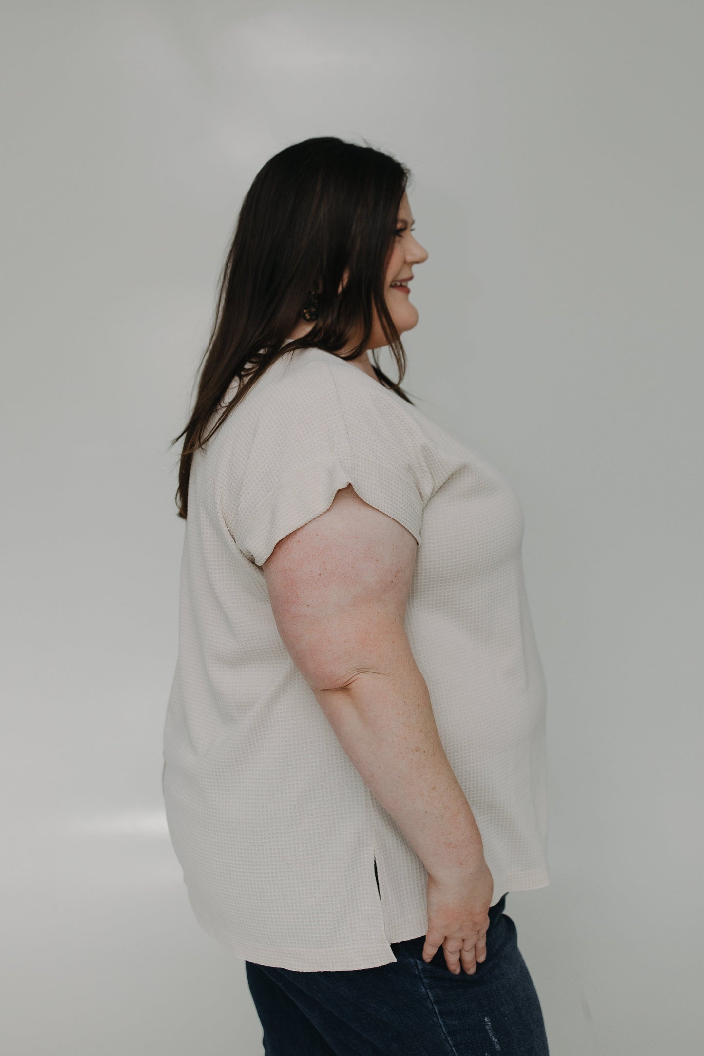 Woman wearing a light-colored blouse against a plain background
