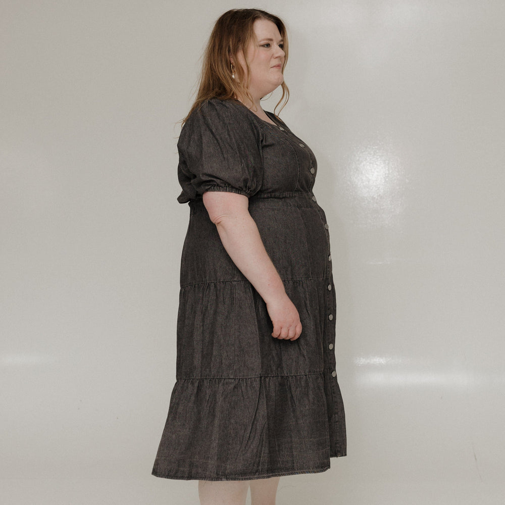 Woman wearing a dark gray dress standing against a white background