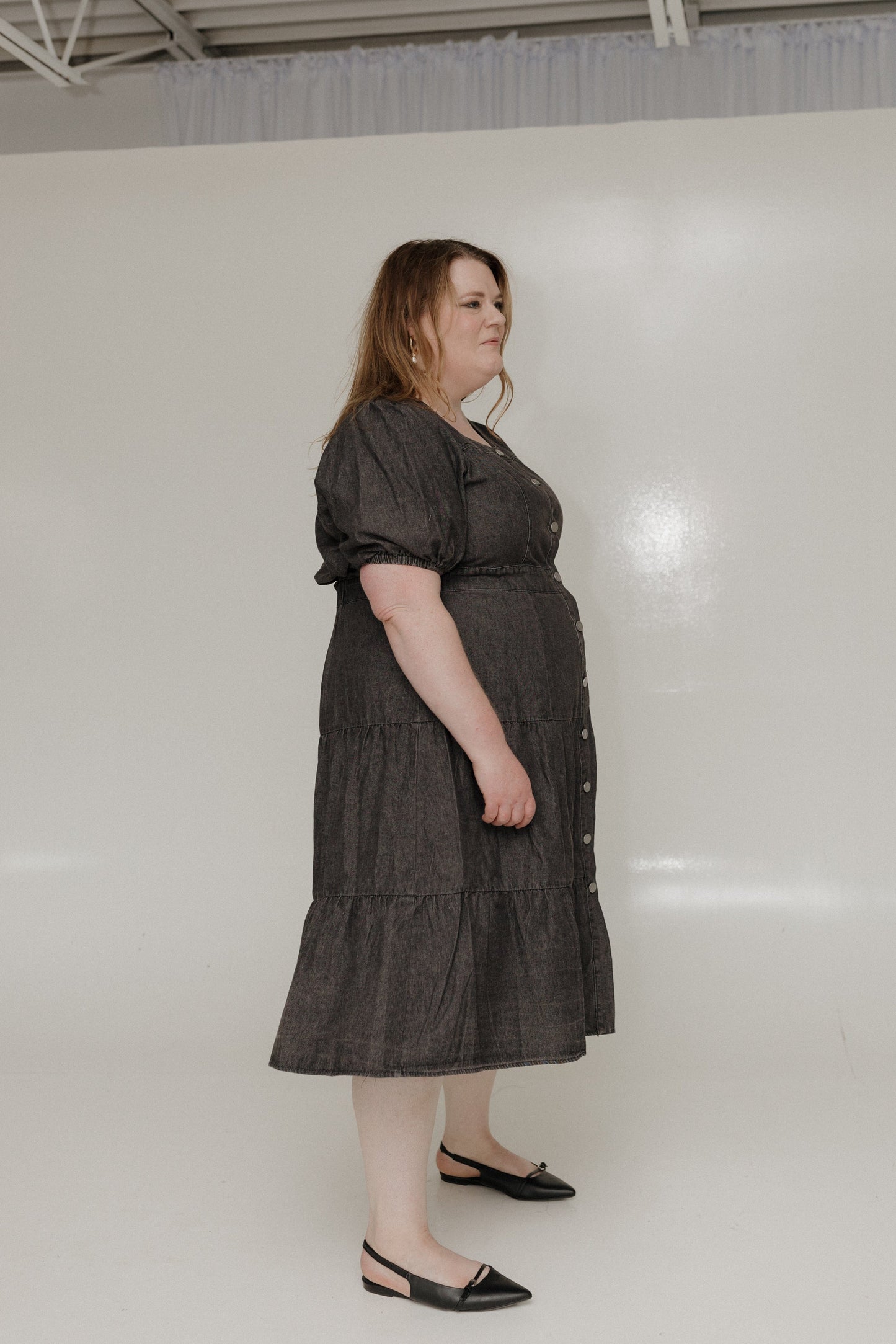 Woman wearing a dark gray dress standing against a white background