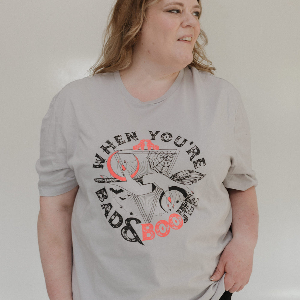 "WHEN YOU'RE BAD AND BOOJEE" GRAPHIC TEE woman wearing a gray t-shirt with graphic design and text on a plain background at Love Marlow