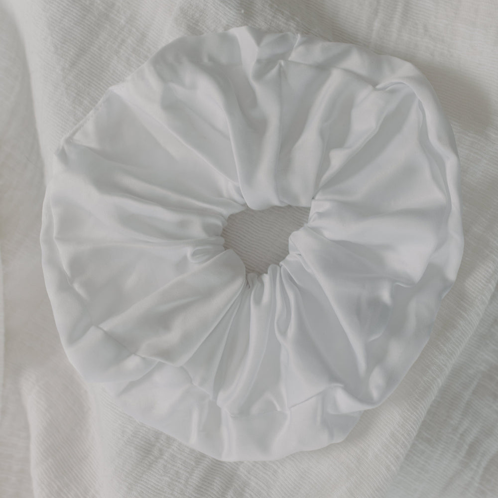 White scrunchie on a textured white fabric background