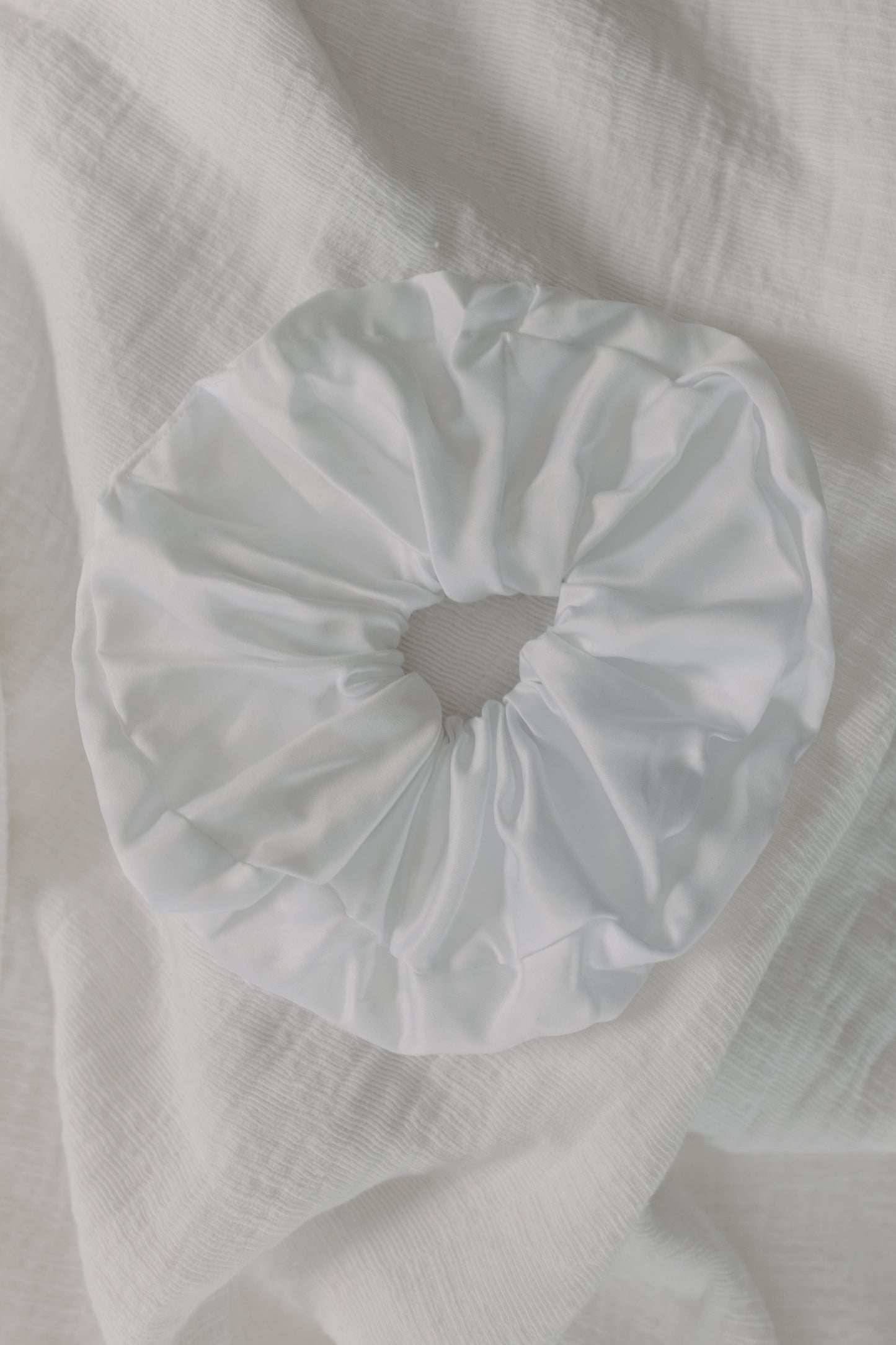 White scrunchie on a textured white fabric background