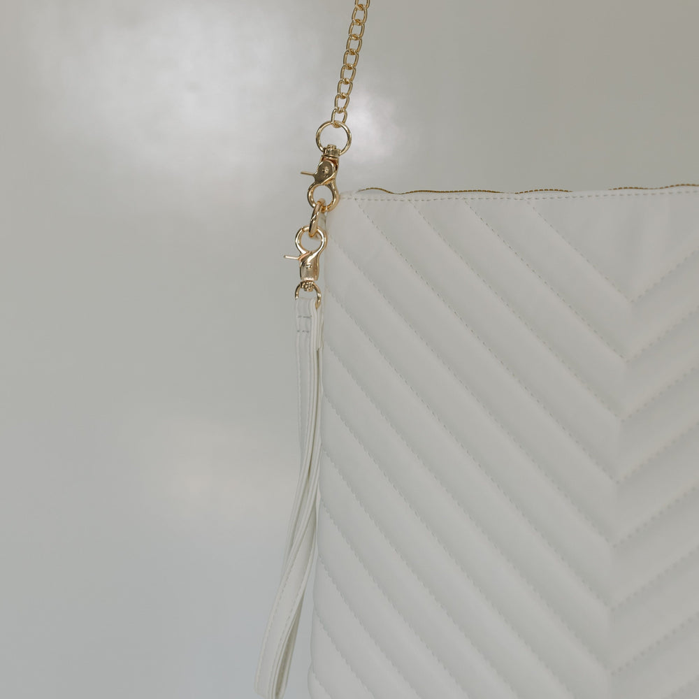 White Quilted Laptop Sleeve Crossbody purse details against a white surface.