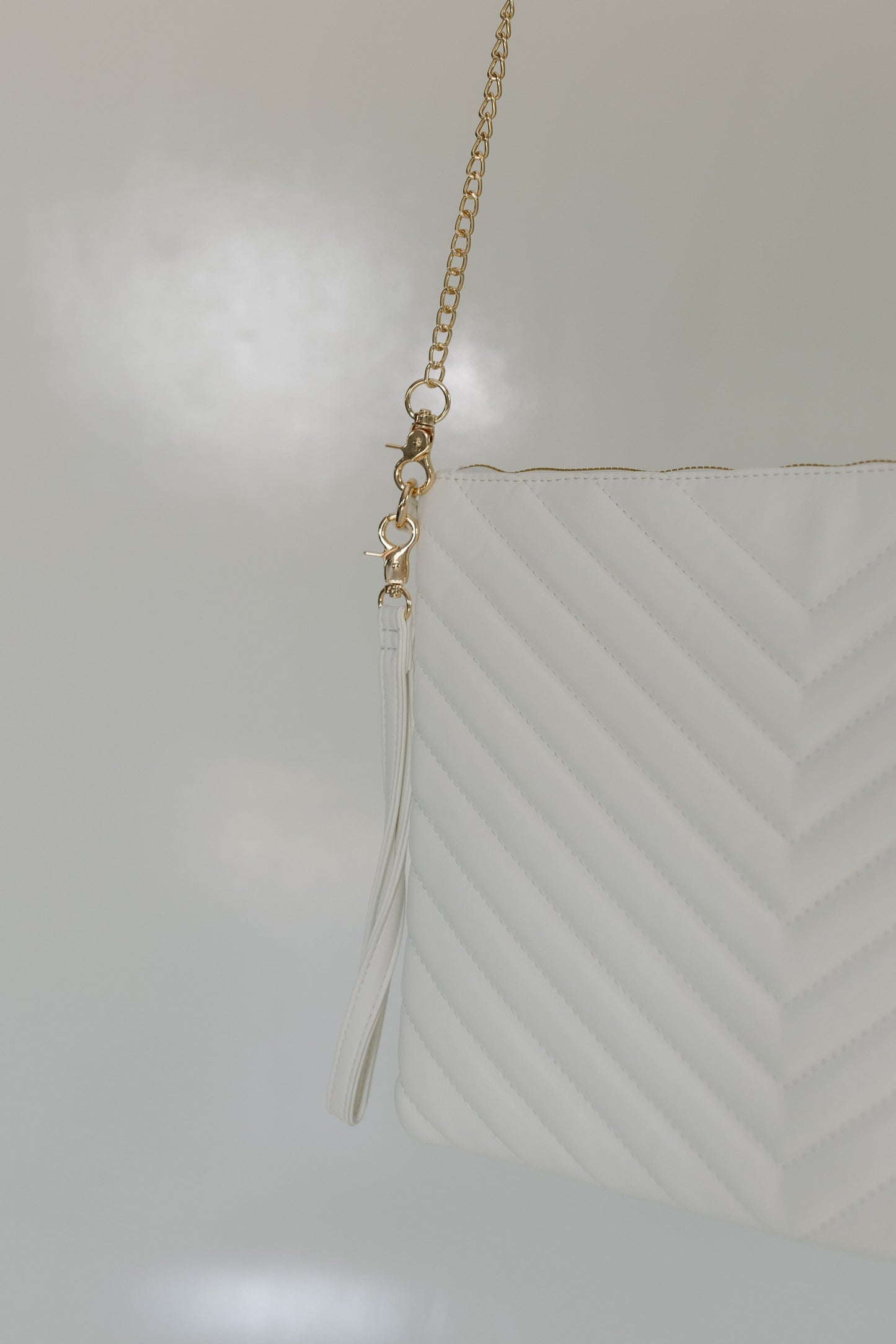 White Quilted Laptop Sleeve Crossbody purse details against a white surface.