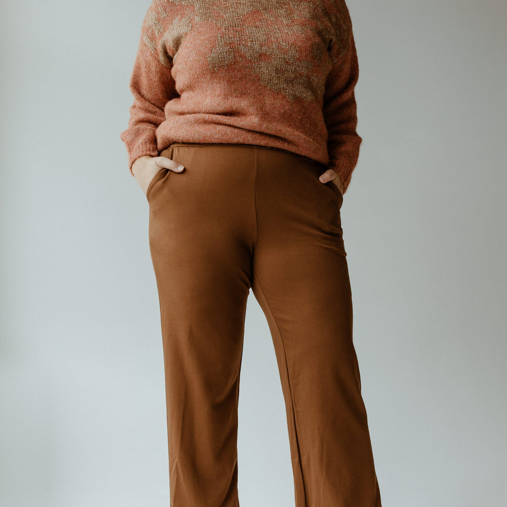 A person stands confidently with hands in pockets, wearing a maroon sweater, Yesta's WIDE LEG TREGGING WITH POCKETS IN TALL featuring a stretchy waistband, and white ankle boots, set against a plain background.