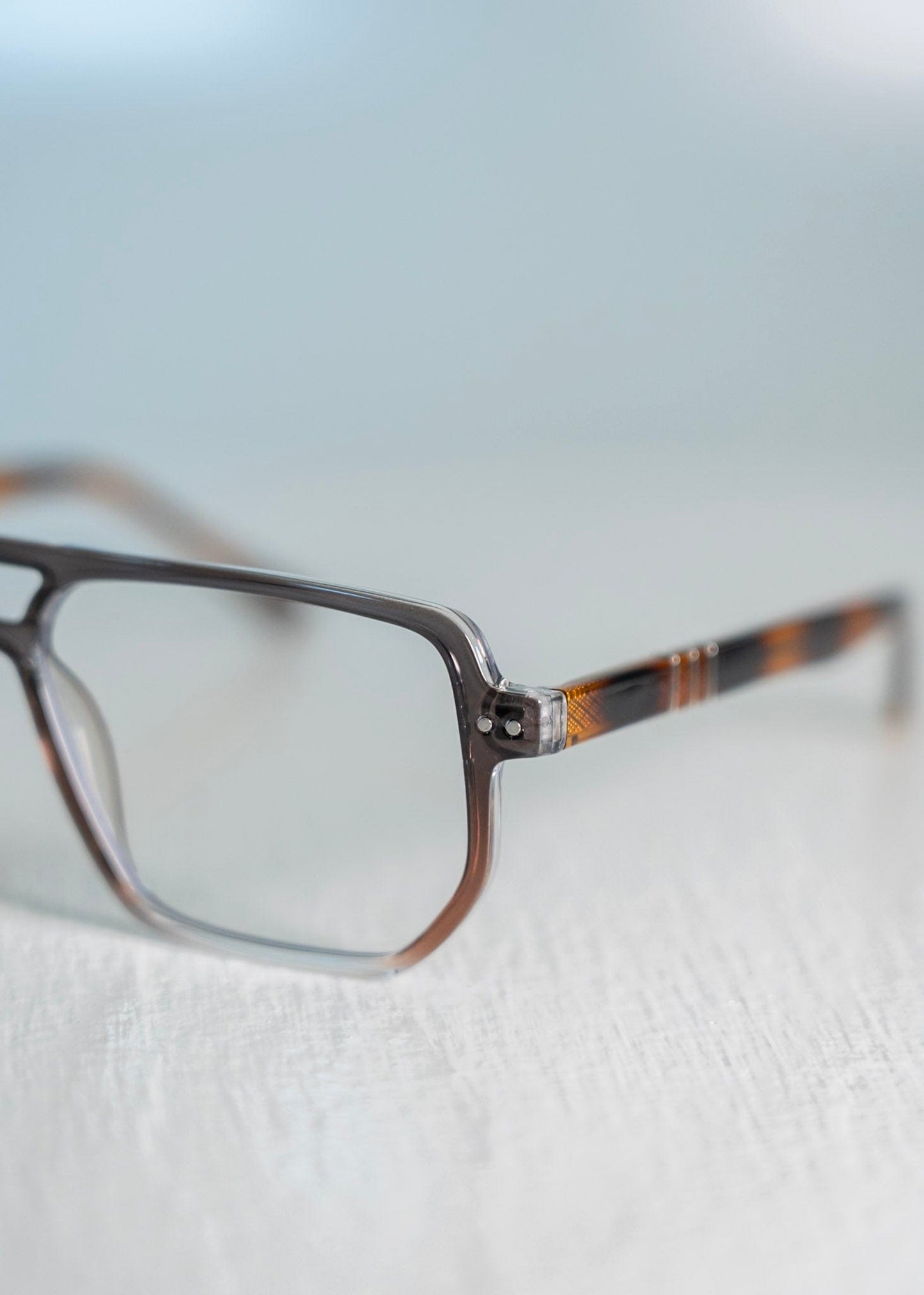 close up of blue light glasses with a tortoiseshell frame on a light background