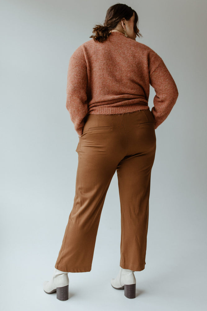 A person wearing a brown sweater, Yesta's WIDE LEG TREGGING WITH POCKETS IN TALL featuring a stretchy waistband, and white boots is standing with their back turned.