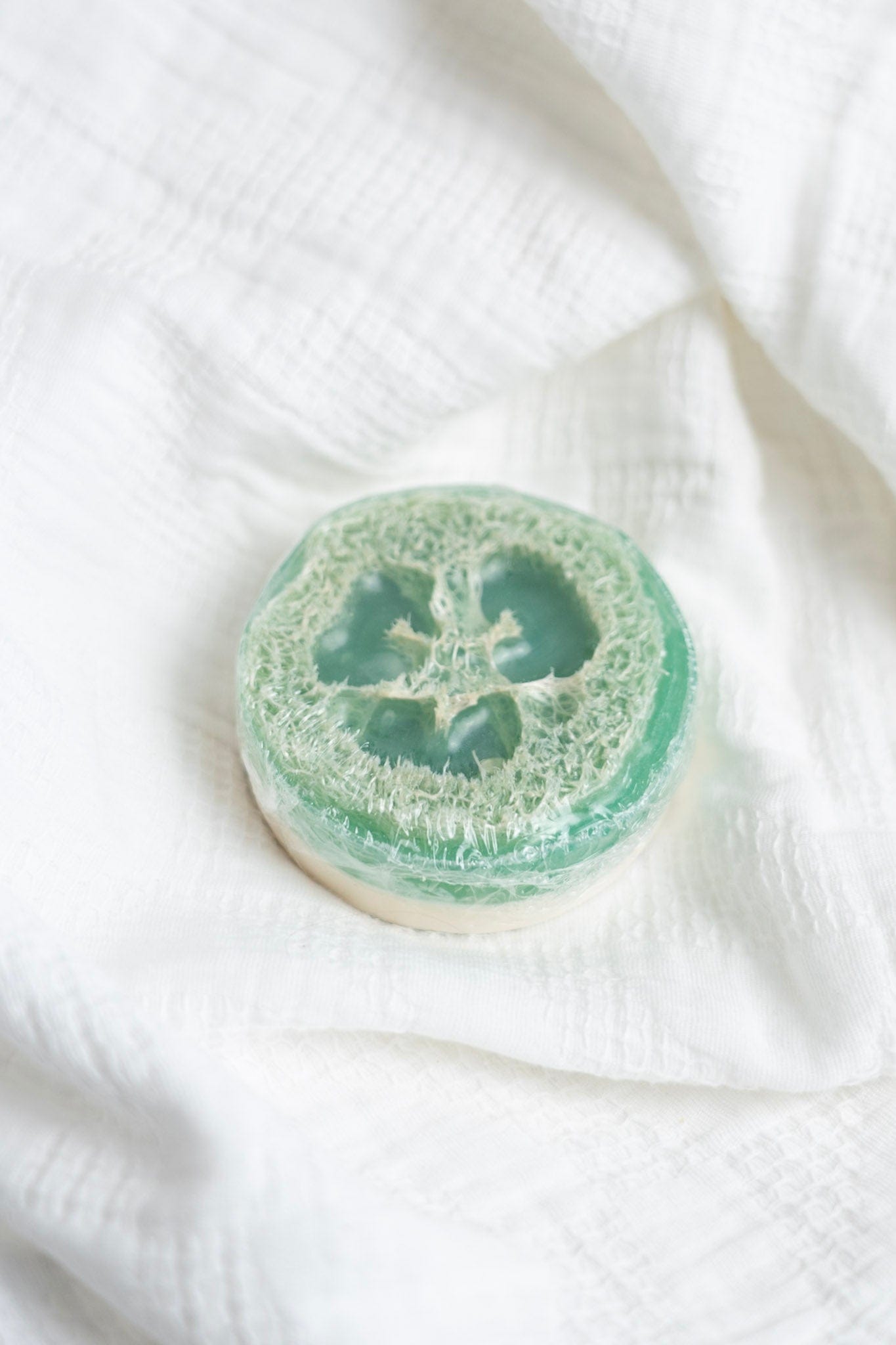 Green loofah sponge soap on a white fabric background