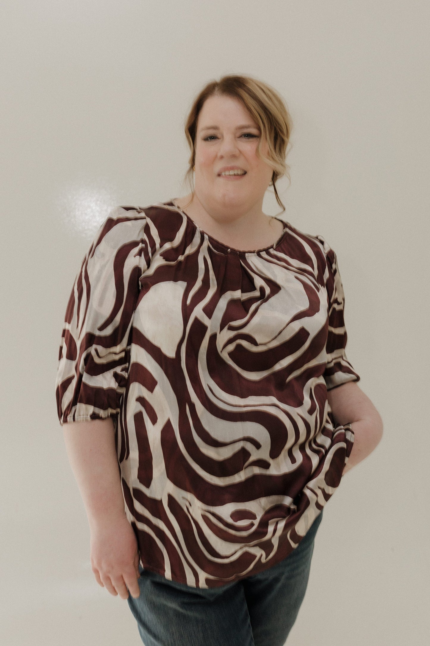 Person wearing a brown and white patterned shirt against a plain background