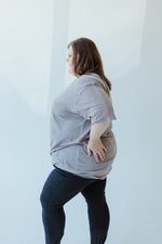 Someone with long hair wearing the "WORD OF ADVICE DON'T CROSS ME" graphic tee by Love Marlow and black pants, displaying a subtle vintage wash as they face away from the camera in a well-lit room.