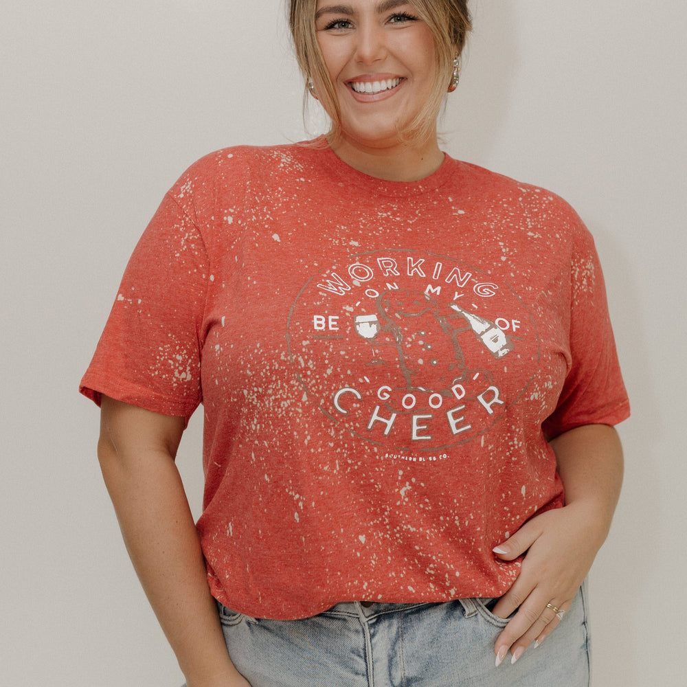 Woman wearing a red t-shirt with text and graphics, standing against a plain background