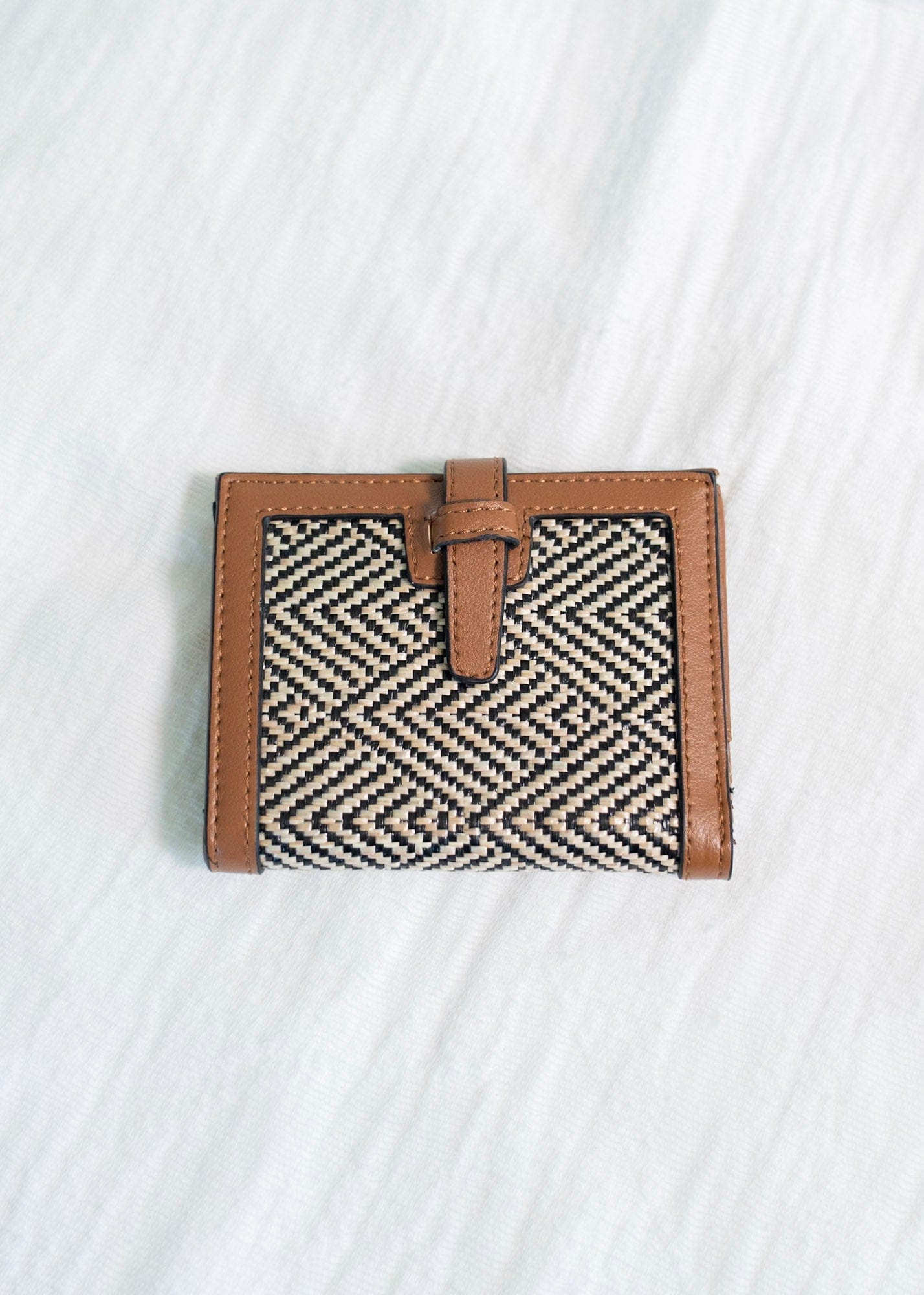 A classic pattern with a color twist makes this unique clutch simply understated. The classic black and natural color is a staple for your purse collection! Plus, so much room for your cards and cash! It has a slip closure and supple faux leather with a fun woven arrow pattern! 