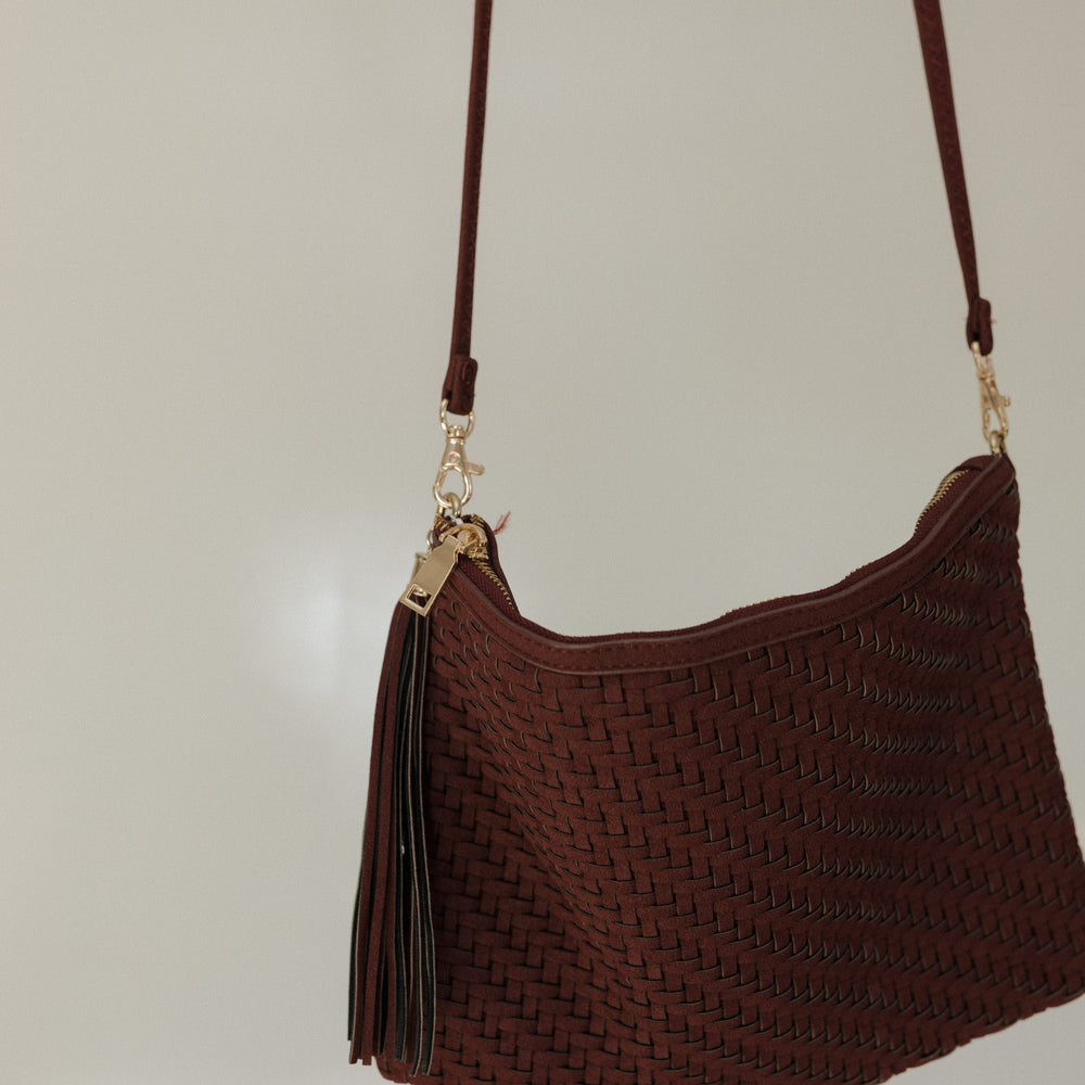 Brown textured handbag with a strap on a light gray background