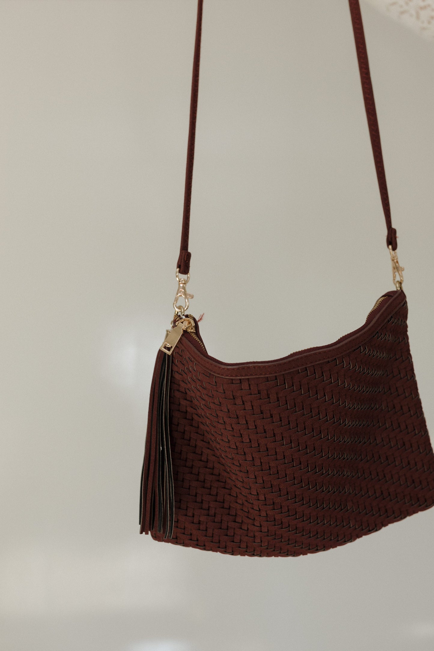 Brown textured handbag with a strap on a light gray background