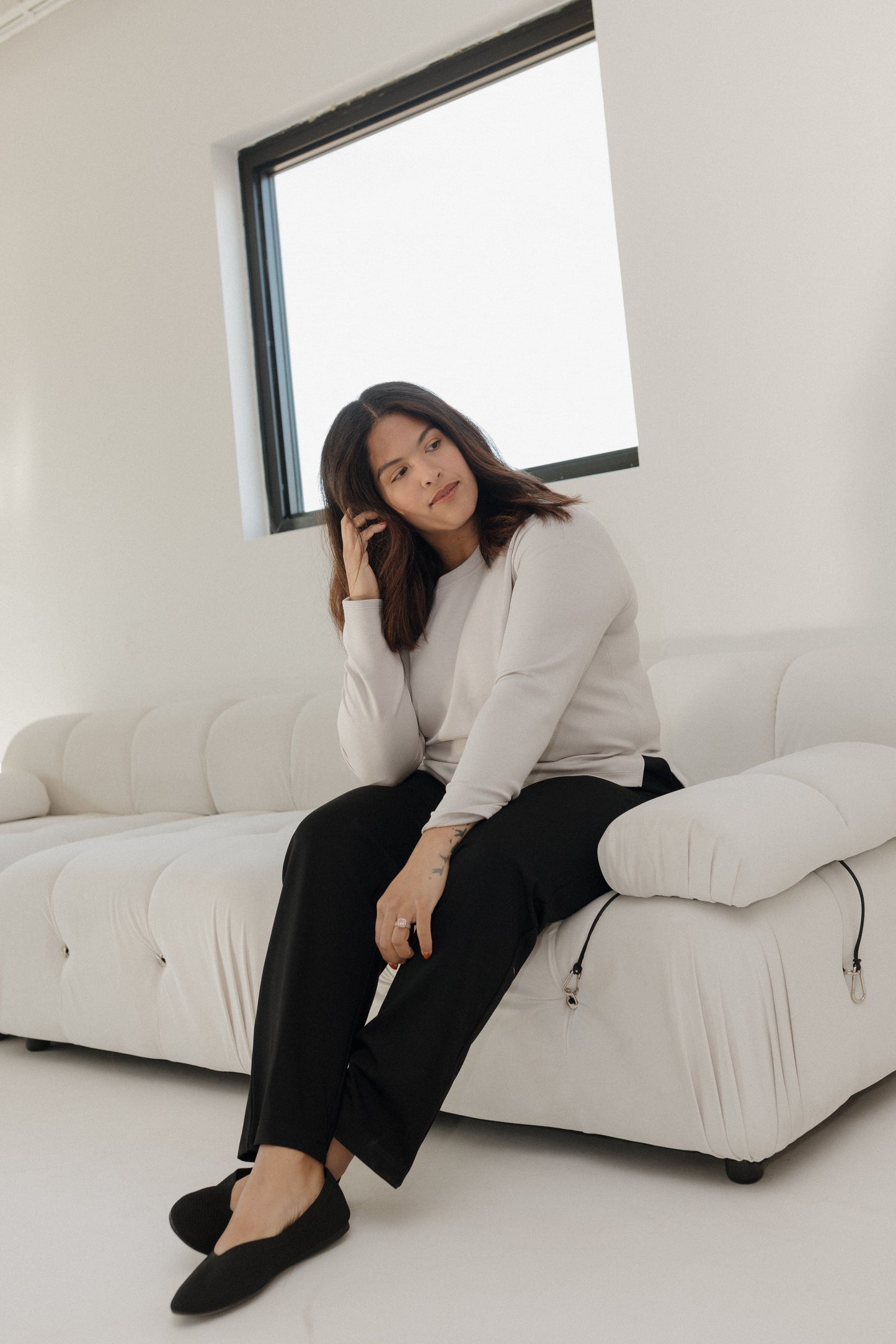 Woman sitting on a white couch in a minimalistic room