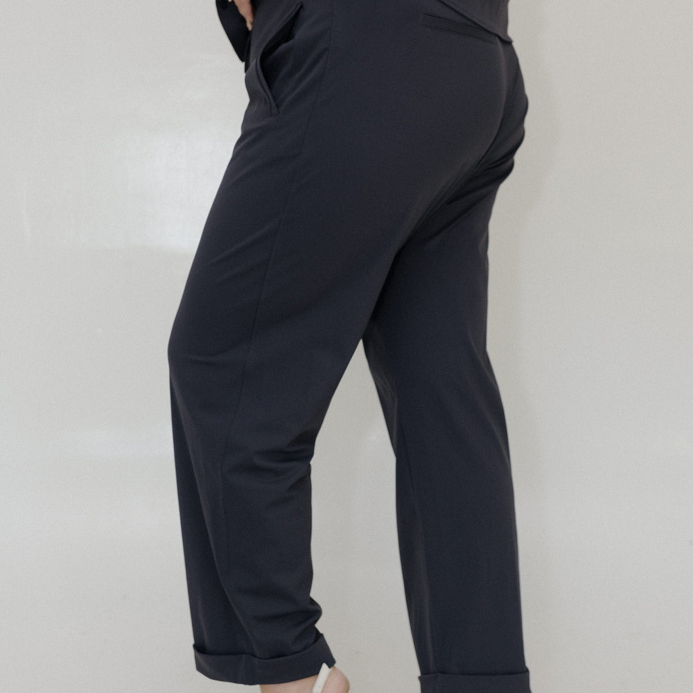 Person wearing black pants and white shoes on a plain background