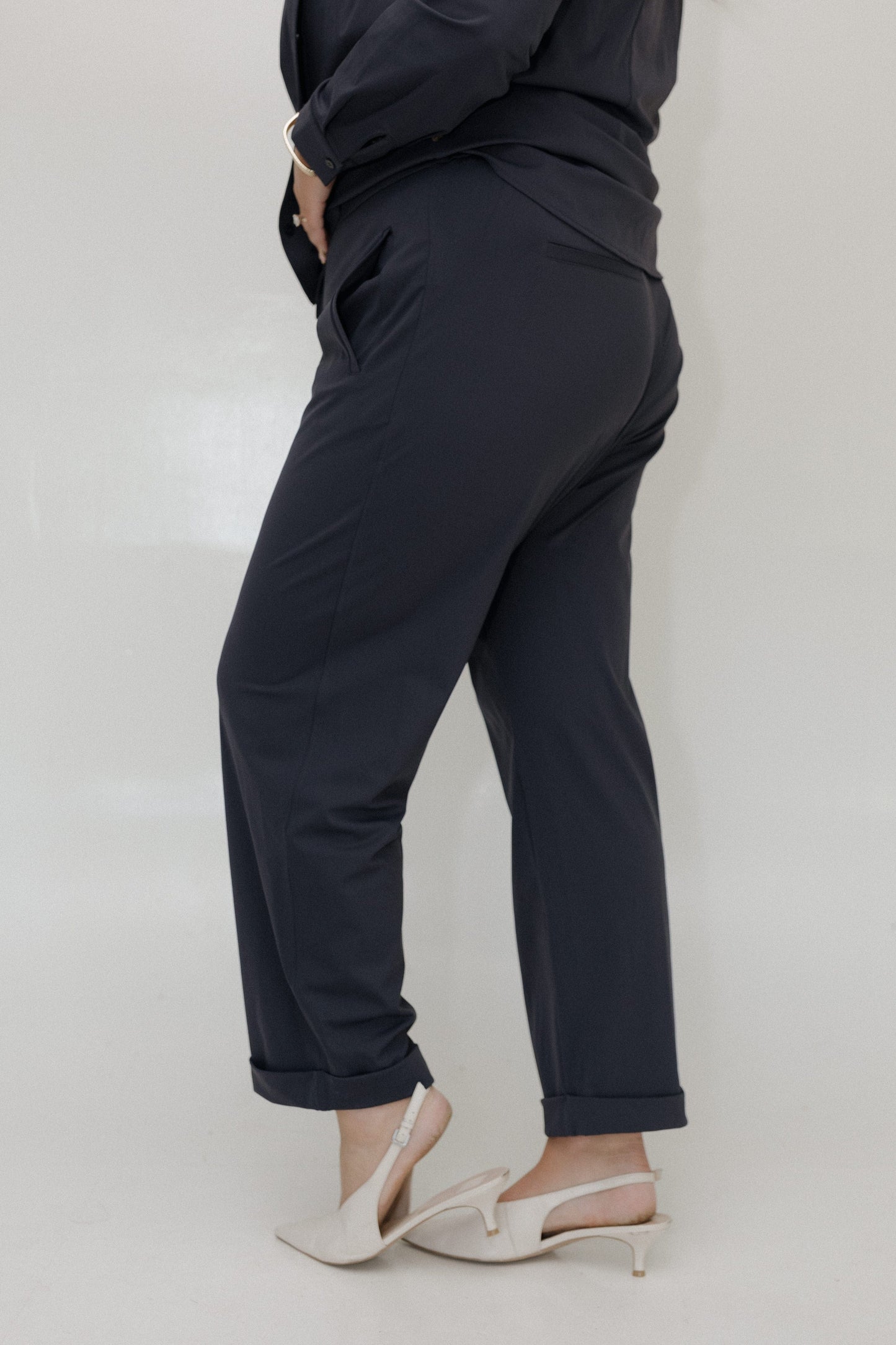 Person wearing black pants and white shoes on a plain background