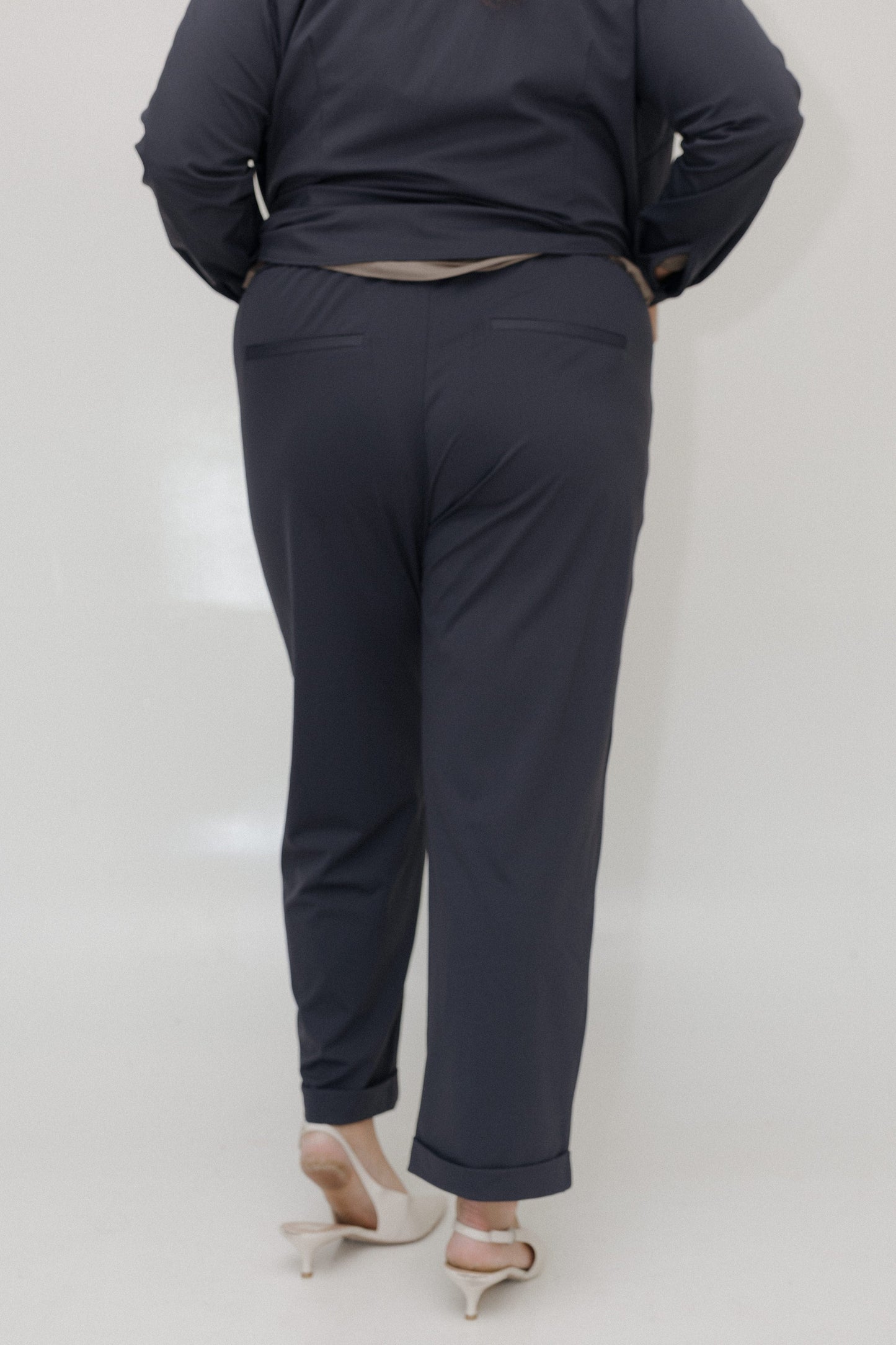 Person wearing a dark blue outfit with pants on a plain background