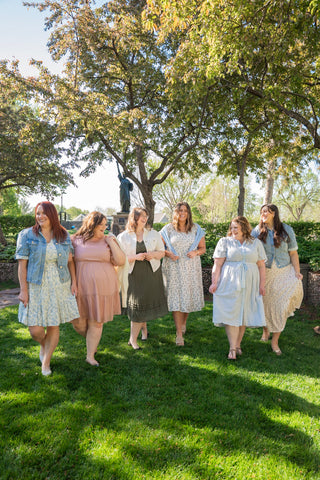 Group of women standing on grass with trees in the background