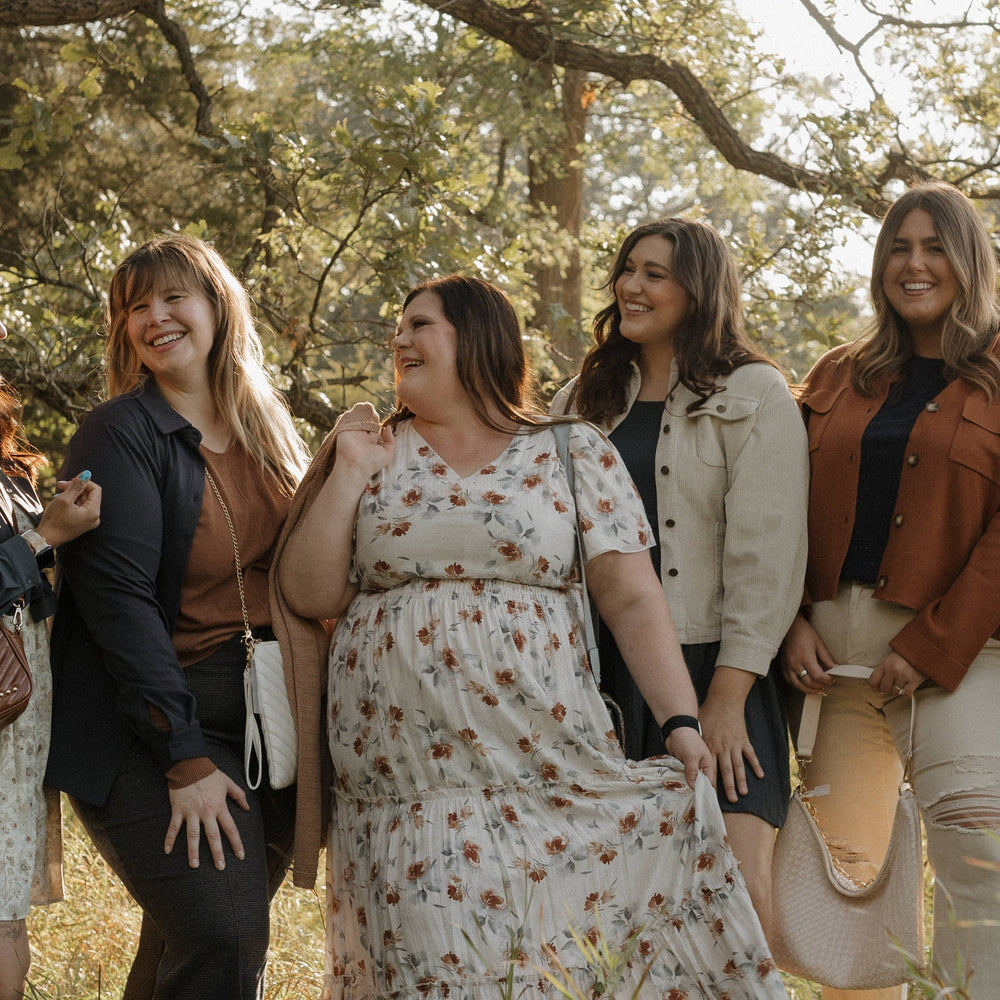 Group of women standing together in a field with trees in the background