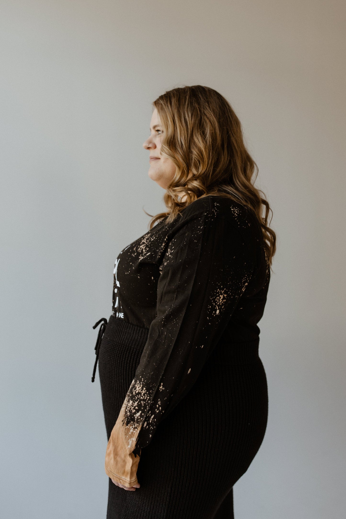 A person with long hair, dressed in a stylish black ensemble that includes Love Marlow's 