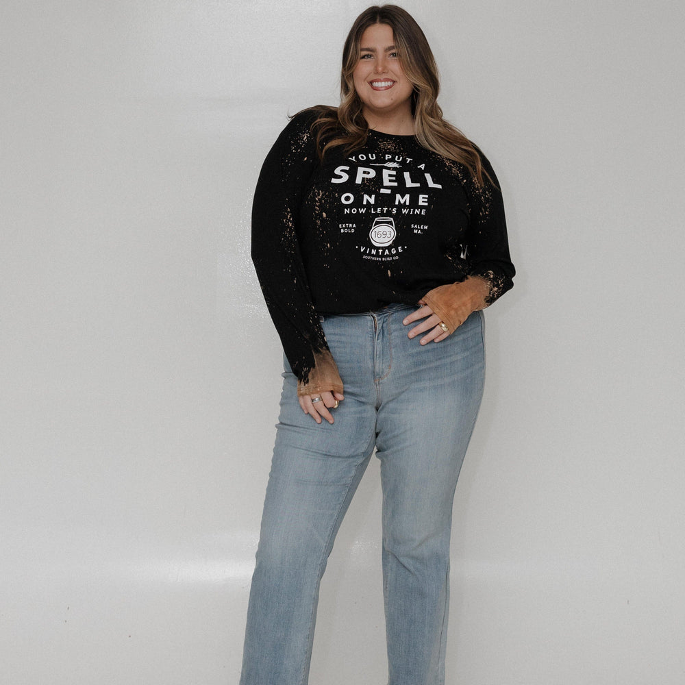 "YOU PUT A SPELL ON ME NOW LET'S WINE" LONG SLEEVE GRAPHIC TEE Woman wearing a black sweatshirt with text and sheer sleeves against a white background at Love Marlow