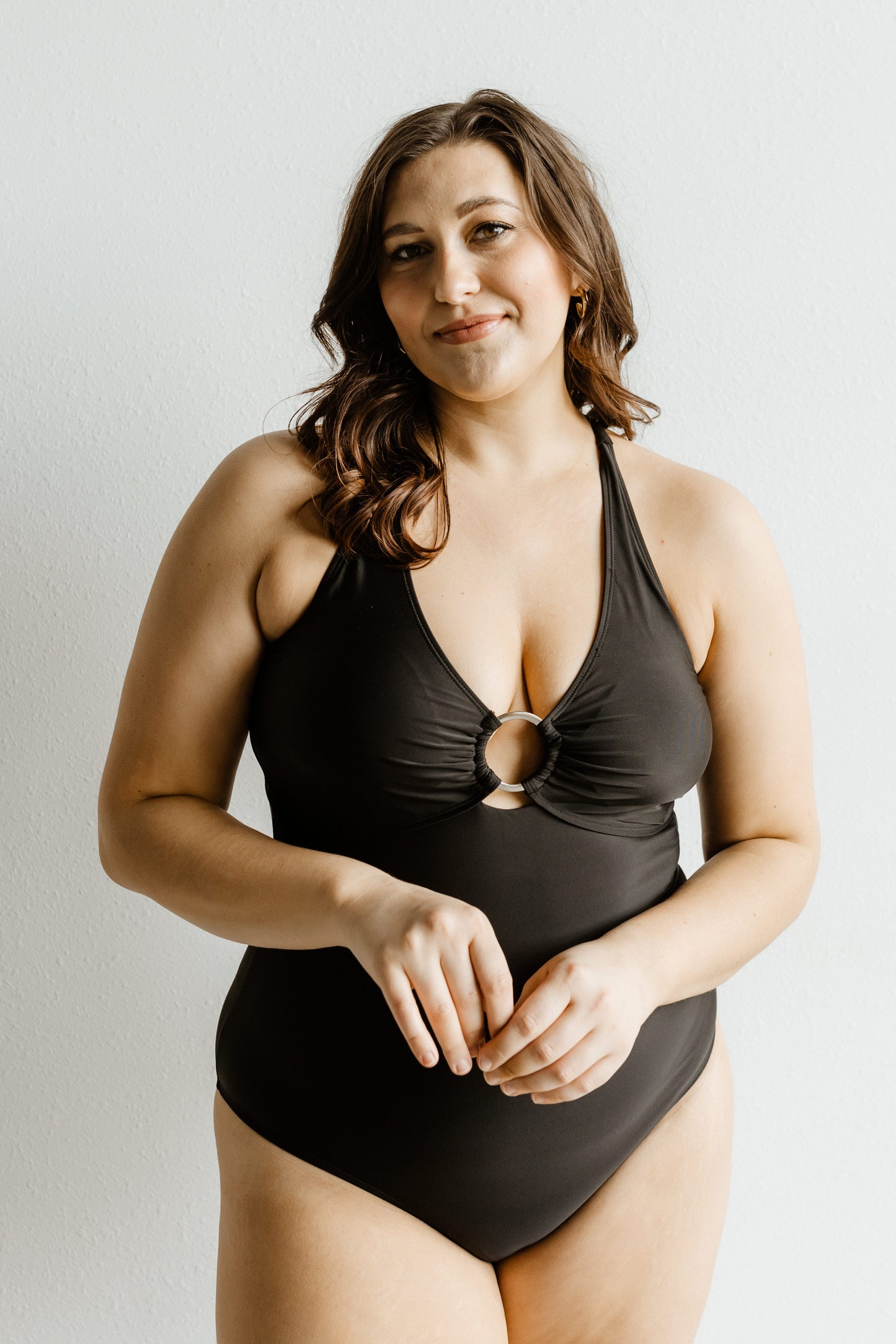 Woman wearing a black swimsuit against a plain background