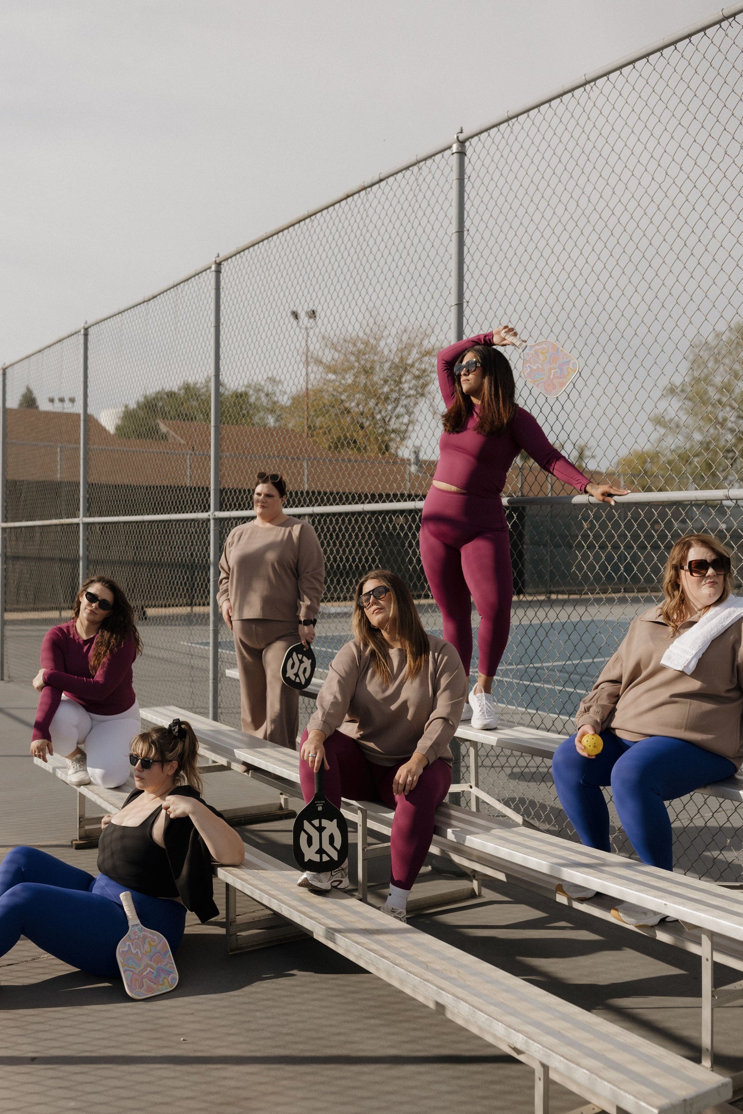 Group of women on bleachers with sports equipment on a tennis court