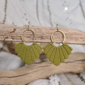 Pair of green, fan-shaped polymer clay earrings with elegant brass hoops, displayed on driftwood against a textured background.